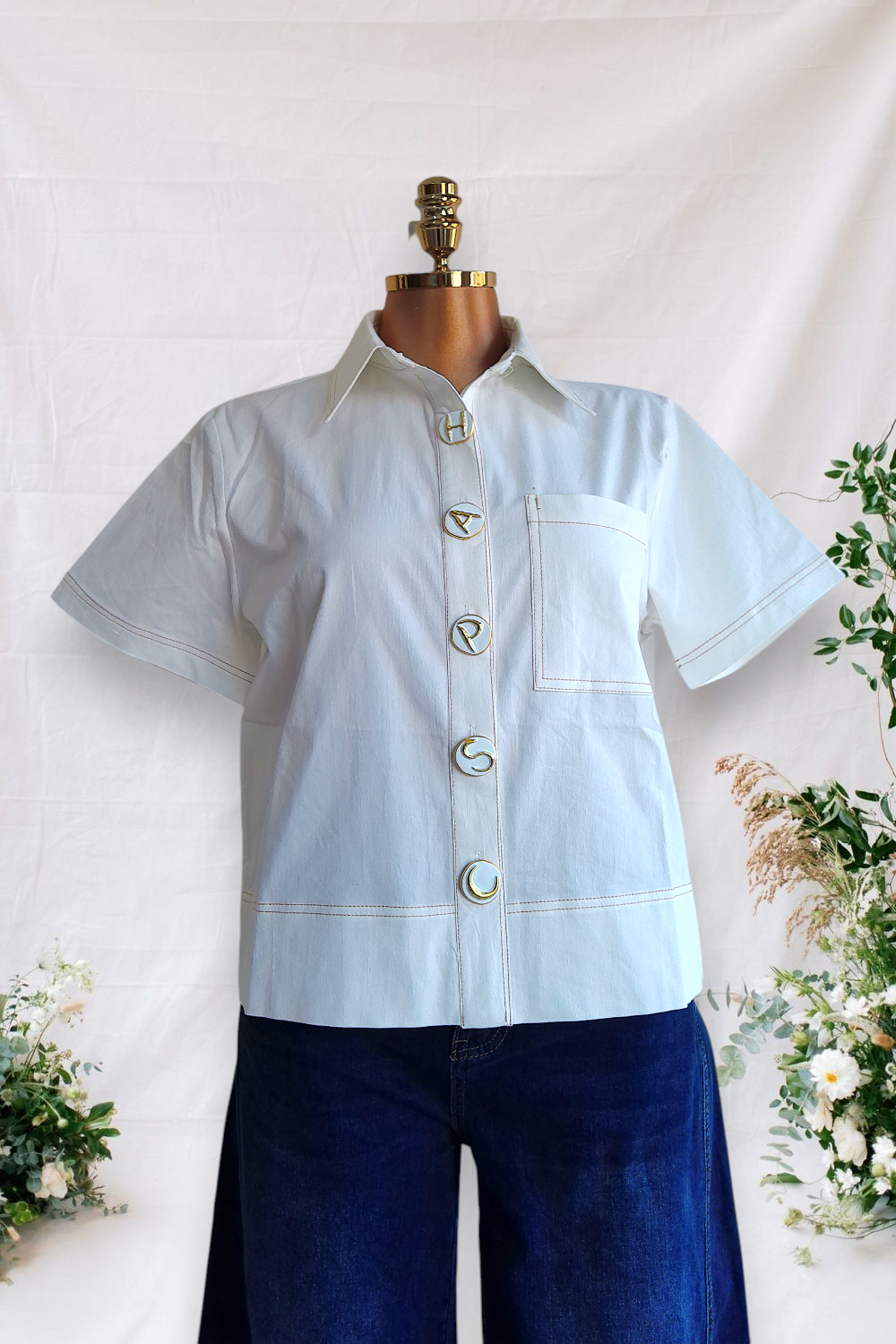 CAMISA BLANCA DE BOTONES BLANCOS CON LETRAS DORADAS