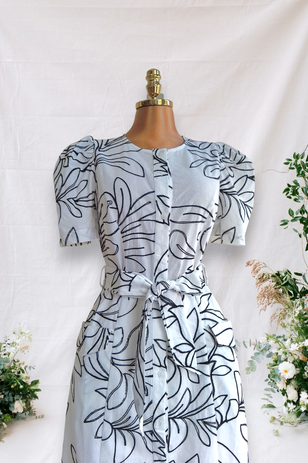 VESTIDO BLANCO DE BOTONES Y DOS BOLSAS ALFRENTE DE BORDADO DE HOJAS NEGRO