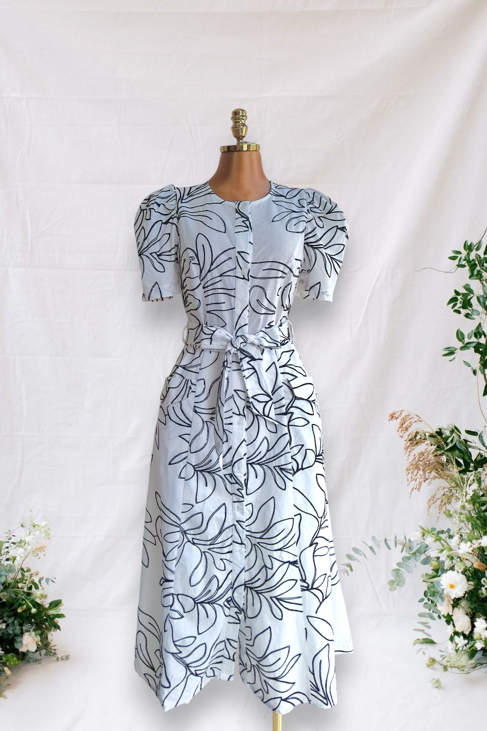 VESTIDO BLANCO DE BOTONES Y DOS BOLSAS ALFRENTE DE BORDADO DE HOJAS NEGRO